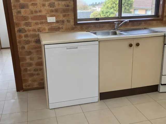 Built-in dishwasher under a kitchen bench beside a sink and tiled floor in Thornton