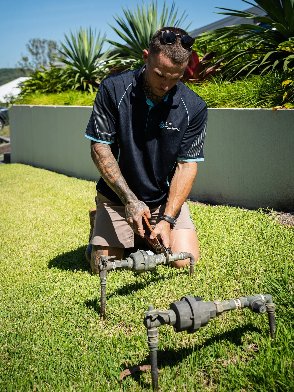 Plumber kneeling at a water meter on a front lawn